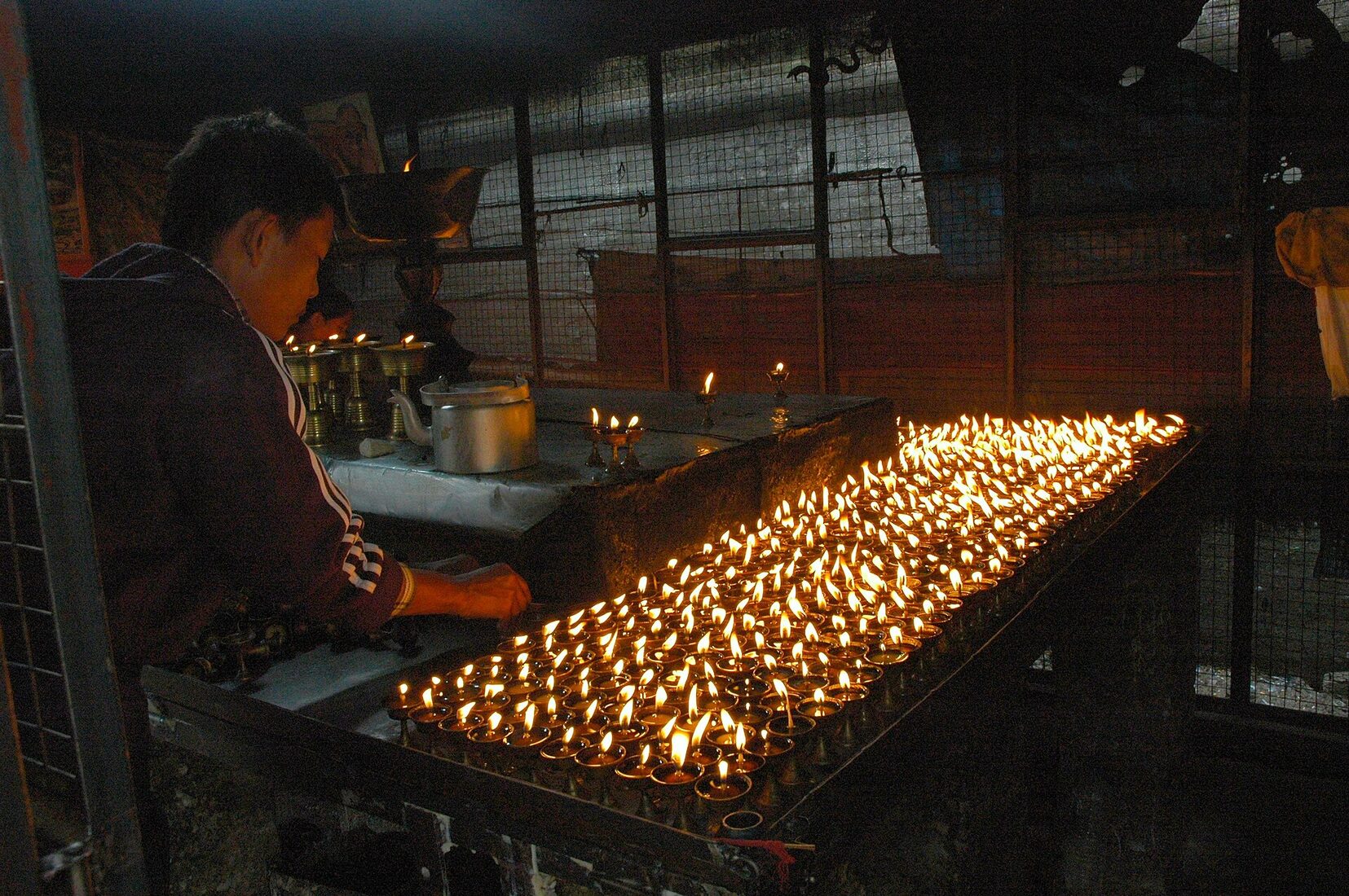 Hundreds of butter lamps laid out in rows, wicks being set for offering
